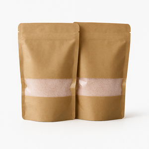 Twee kraft papieren zakken met transparant venster gevuld met rozekaarsenzand, gepresenteerd op een strakke, lichtgrijze ondergrond. Dit product is beschikbaar in vijf kleuren: wit, zwart, grijs, beige en roze.