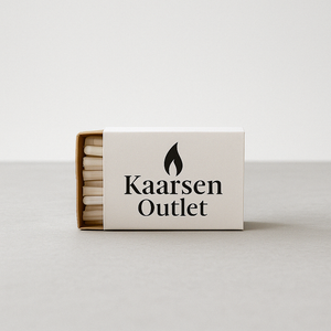 Doosje met witte kaarsenwieken van Kaarsen Outlet, liggend op een lichtgrijze ondergrond met een witte achtergrond. Op het doosje staat een zwart vlamicoon en het logo 'Kaarsen Outlet' gedrukt.