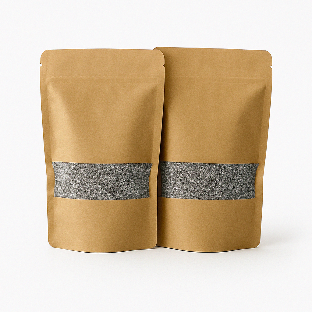 Twee kraft papieren zakken met transparant venster gevuld met grijs kaarsenzand, gepresenteerd op een strakke, lichtgrijze ondergrond. Dit product is beschikbaar in vijf kleuren: wit, zwart, grijs, beige en roze.
