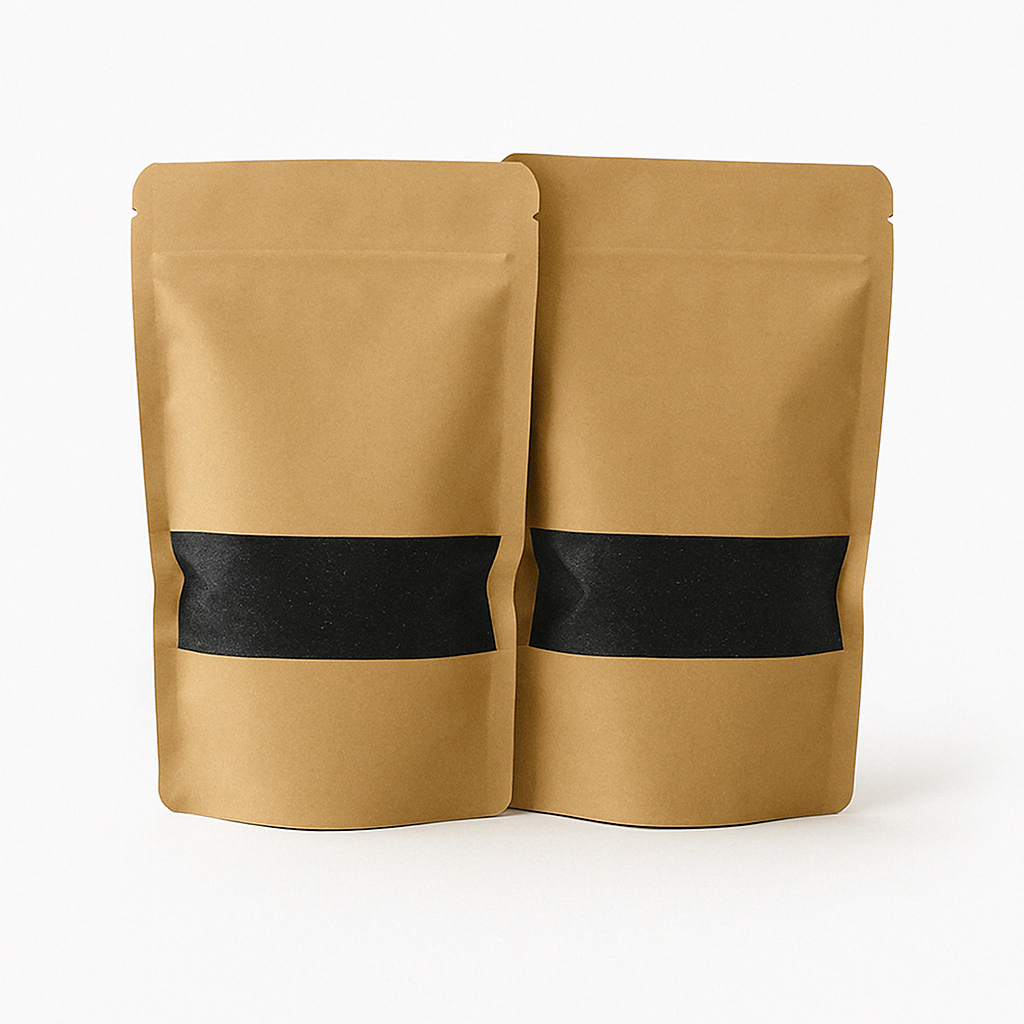Twee kraft papieren zakken met transparant venster gevuld met zwart kaarsenzand, gepresenteerd op een strakke, lichtgrijze ondergrond. Dit product is beschikbaar in vijf kleuren: wit, zwart, grijs, beige en roze.